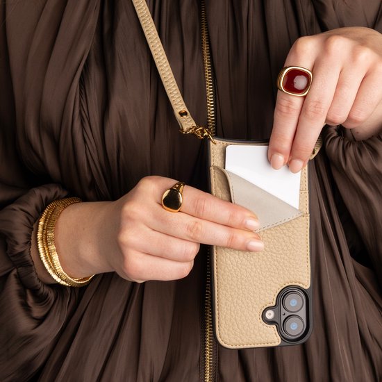 Handen steken een kaart in de pashouder van een beige iPhone 14 Pro backcover met koord.