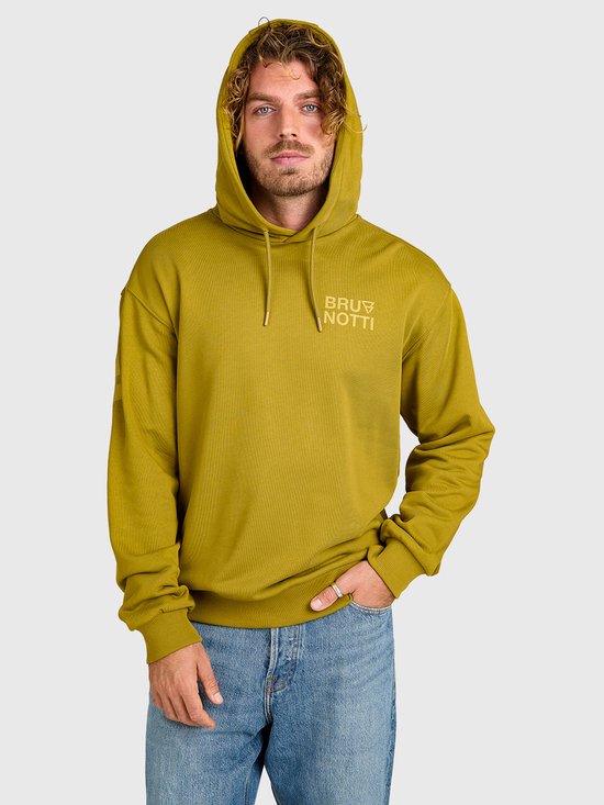 Man draagt een olijfgroene Brunotti hoodie met capuchon, gecombineerd met een blauwe spijkerbroek.