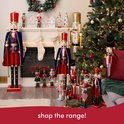 Diverse kerstnotenkrakers, groot en klein, bij een open haard, kerstboom en cadeaus.