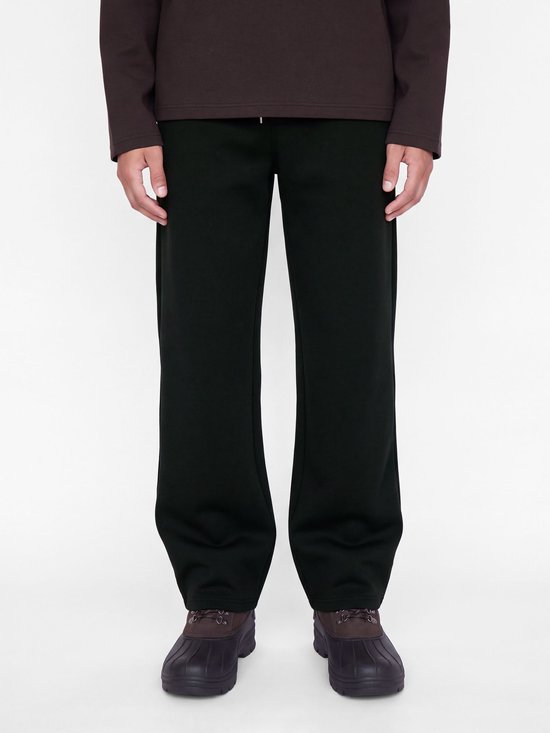 Close-up van een zwarte joggingbroek op een model, gecombineerd met bruine laarzen.
