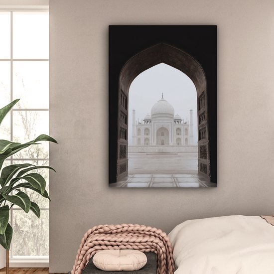 Une peinture du Taj Mahal à travers une arche, au-dessus d'un lit dans une chambre.