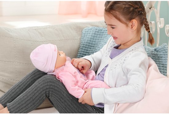 Een meisje houdt een baby-pop in roze kleding vast.