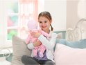 Een meisje knuffelt met een baby-pop in roze kleding.