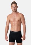 Man met strakke buikspieren en een paardenstaart in een zwarte Muchachomalo boxer.
