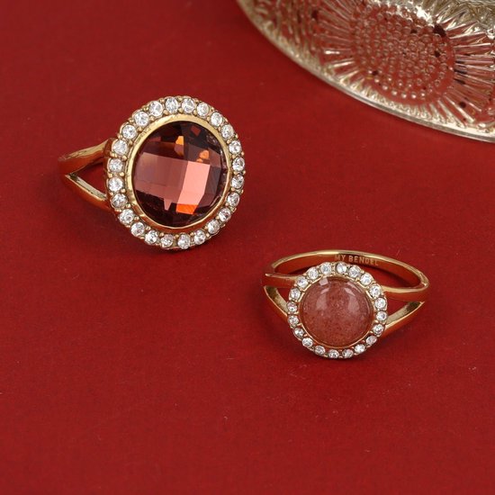 Twee gouden ringen met ronde, donkerrode en roze stenen, omringd door zirkonia's.