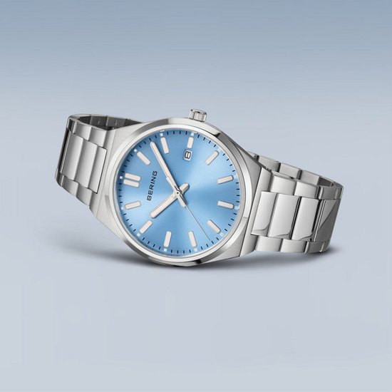 Zilverkleurig herenhorloge met blauwe wijzerplaat. De wijzerplaat heeft een datumweergave. Het horloge heeft een metalen band.