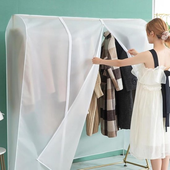 Vrouw in wit jurkje opent doorzichtige kledinghoes, met bruine en beige ruitjes jassen zichtbaar.