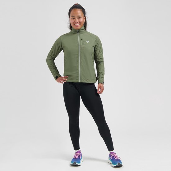Model met olijfgroen damesjack, zwarte legging en gekleurde hardloopschoenen.