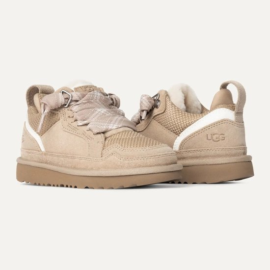 Beige UGG sneakers met bruine zool, schapenwollen voering en stoffen veters met ruitpatroon.