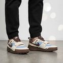 Man met zwarte broek en bruine, beige, lichtblauwe sneakers met klittenband.
