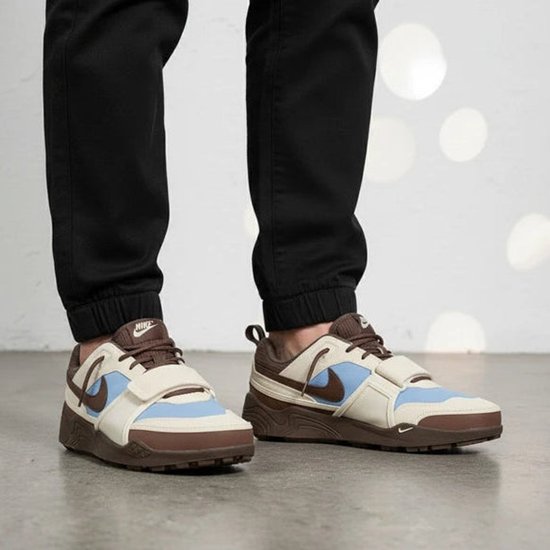 Man met zwarte broek en bruine, beige, lichtblauwe sneakers met klittenband.