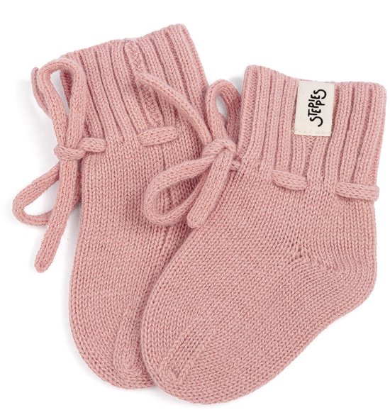 Een paar roze gebreide babyslofjes van Steppies met striklint, op een witte achtergrond.