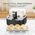 Emerio eierkoker zwart met transparante deksel. Op een bord liggen drie gekookte eieren: zacht, medium en hard. "Gekookt Naar Jouw Voorkeur".
