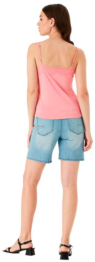 Model draagt een roze top met kanten rand van achteren, gecombineerd met een spijkerbroek.