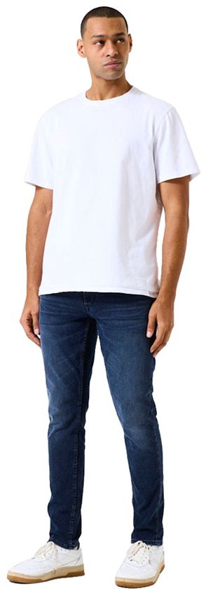Man draagt een effen witte T-shirt en een donkerblauwe slim fit jeans.