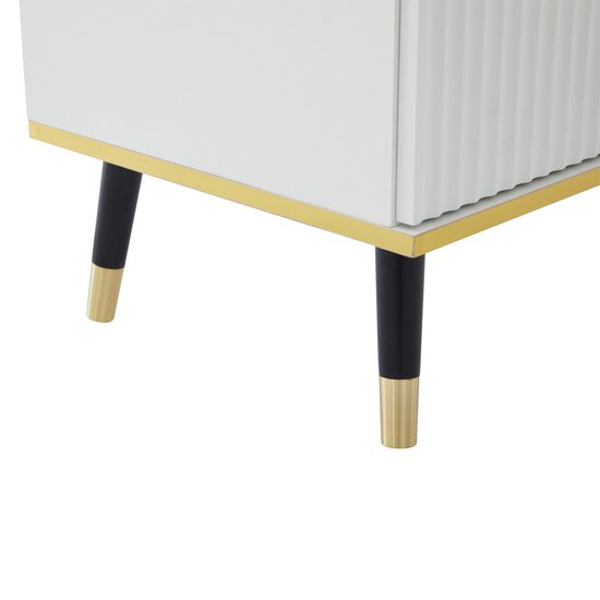 Detail van zwarte pootjes met gouden dopjes en gouden randen op een witte tv-kast.