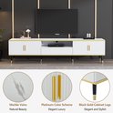 Witte tv-kast met marmerlook blad, gouden accenten, verticale ribbels, gouden handgrepen en zwarte poten.