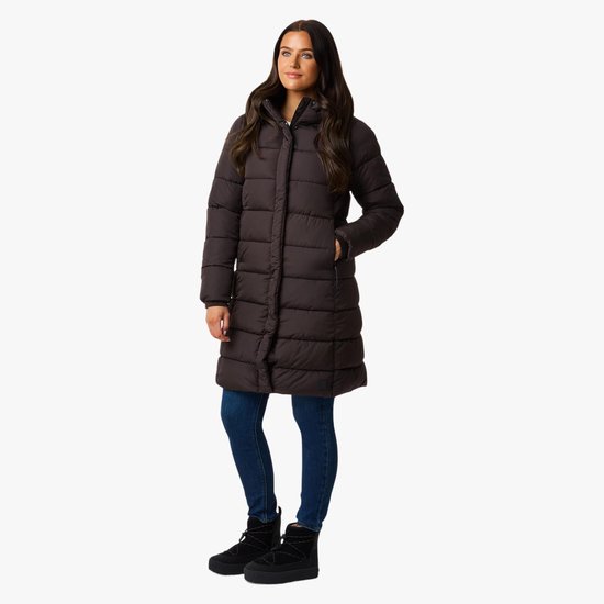 Model draagt een bruine, gewatteerde winterjas voor dames tot op de knie, gecombineerd met blauwe jeans en laarzen.
