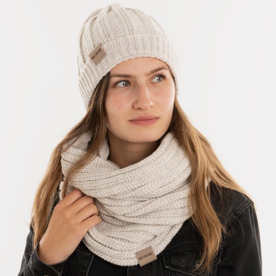 Model met off-white gebreide muts en sjaal, met beige labels.