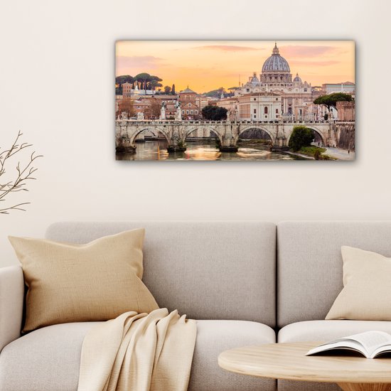 Canvas van de Sint-Pietersbasiliek en de Ponte Sant'Angelo in Rome bij zonsondergang, getoond boven een neutrale bank.
