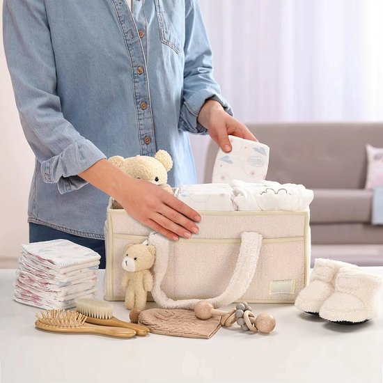 Persoon rangschikt babyartikelen in een beige commandomand, inclusief luiers, schoentjes en borstels.