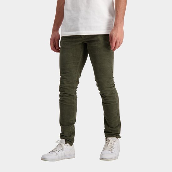 Man met groene corduroy jeans en witte sneakers, van voren gezien.