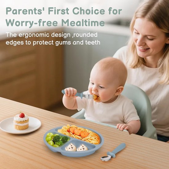 Baby met een blauw bord, eet met een bijpassende lepel. Een vrouw kijkt toe.