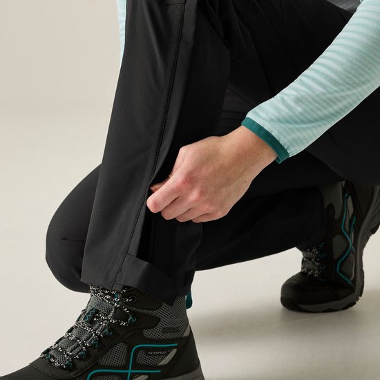 Close-up van een zwarte outdoorbroek met een rits op de broekspijp.