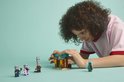 Een kind met krullend bruin haar bouwt aan de LEGO Minecraft woestijnset met illagers.