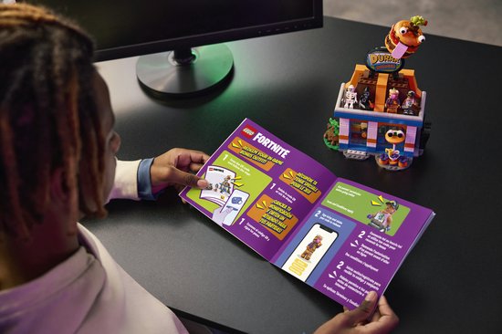 Personne lisant un livret LEGO Fortnite avec une offre pour une tenue en jeu et un restaurant construit
