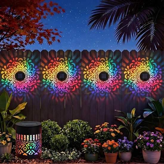 Een donkere houten schutting verlicht door vier solar mandala wandlampen en een cilindrische solar lamp op de grond, met een nachtelijke tuin.