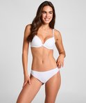 Model in witte voorgevormde beha met strikje en hanger tussen de cups.