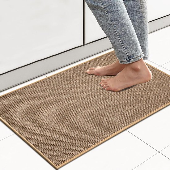Blote voeten van een persoon die op een beige keukenmat staat bij een keuken aanrecht.