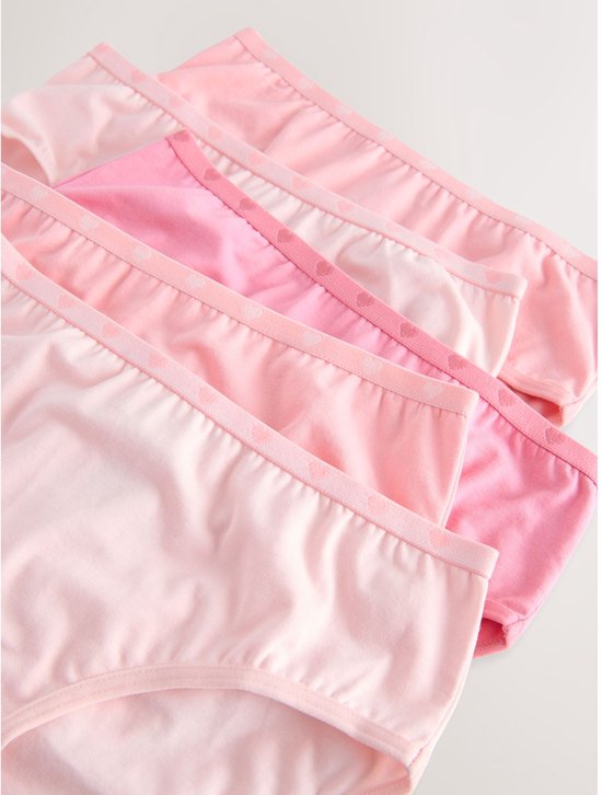 Detailopname van de tailleband van meerdere roze slips met hartjespatroon.