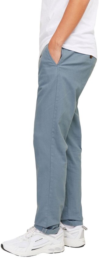 Zijaanzicht van een man in een grijze chino broek met subtiel patroon en witte sneakers.