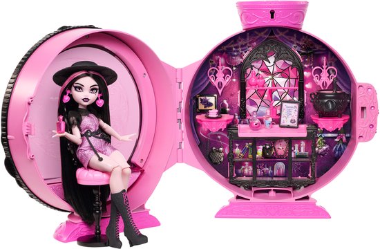 Draculaura-pop zit in een roze, ronde speelkoffer die openklapt. Ze draagt een zwarte hoed en een glinsterend roze pakje.