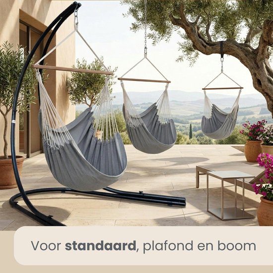 Grijze hangstoelen aan een standaard, plafond en boom, met uitzicht op de bergen.
