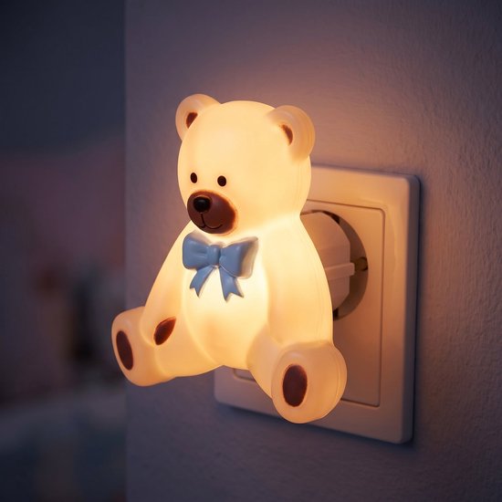 Teddybeer nachtlampje met blauwe strik, brandend in stopcontact, zacht warm wit licht.