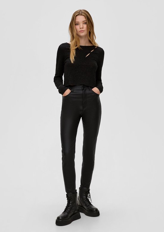 Model draagt zwarte gecoate broek, zwarte glittertop en zwarte veterlaarzen met grove zool.