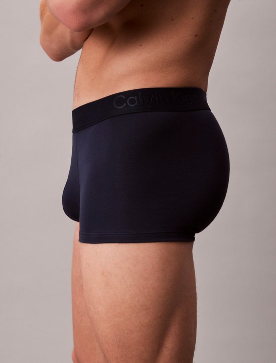 Zijaanzicht van een man in donkerblauwe Calvin Klein boxershort.