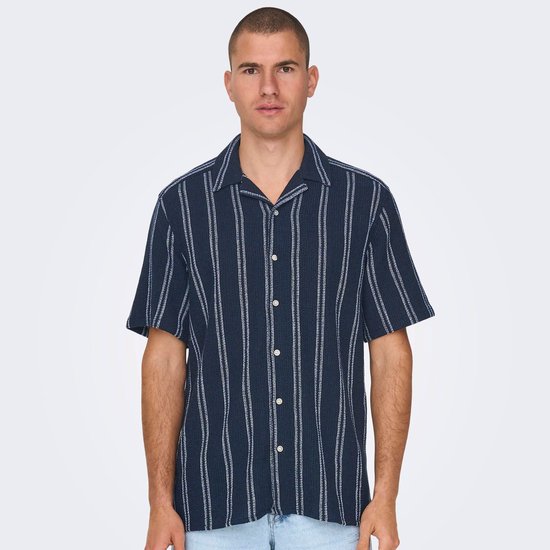 Man in donkerblauw gestreept overhemd en lichtblauwe jeans, zijkant.