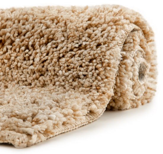 Rolled up beige bath mat with a fluffy texture and stitched edge.