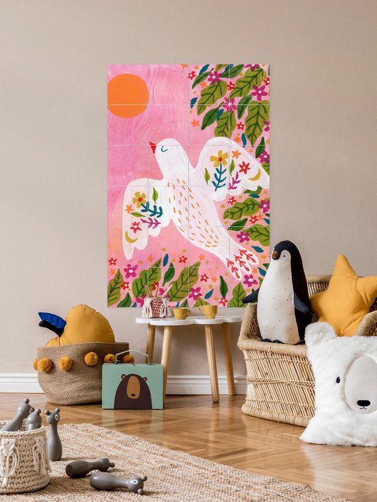 Kleurrijke IXXI muurkunst van vogel tussen bladeren in een interieur met rotanmeubels.