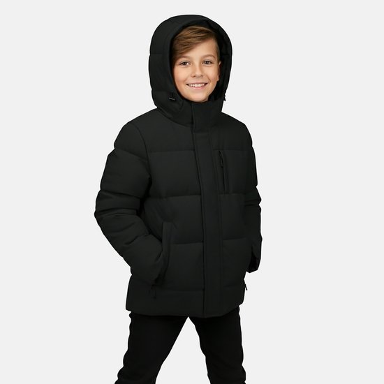 Jongen met zwarte gewatteerde jas met capuchon, staand met handen in de zakken.