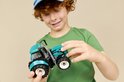 Jongen met krullend haar houdt een felgroene tractor vast.