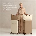 Vrouw met een crème en beige SUITSUIT koffers en bijpassende reistassen. Textiel.