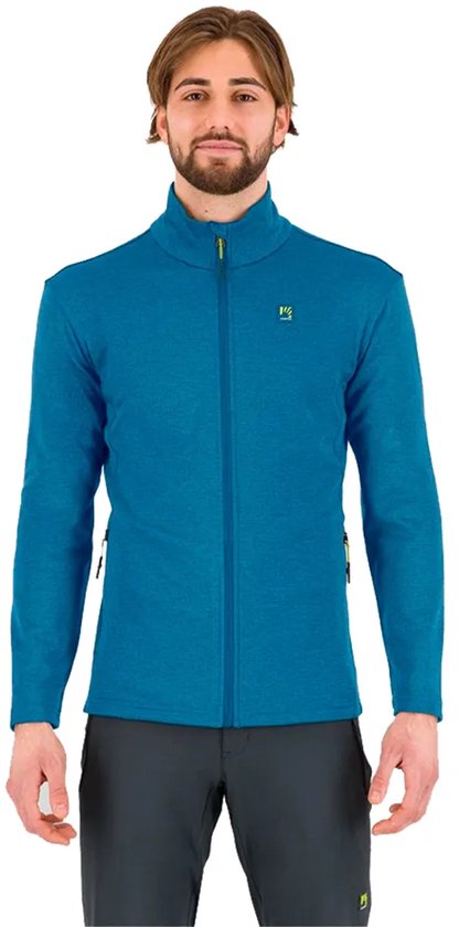 Un homme barbu portant une veste polaire bleue zippée à manches longues. La veste a un logo jaune sur la poitrine gauche.
