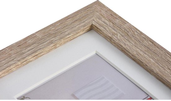 Détail d'angle d'un cadre photo en bois brun clair avec un passe-partout blanc.