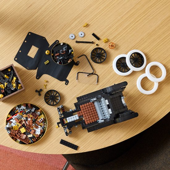 Onderdelen en bouw van de LEGO Icons Ford Model T op een houten tafel.