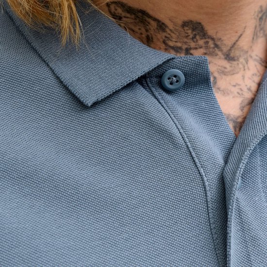 Close-up van de kraag en knoop van een blauwgrijze poloshirt.